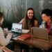 Jovenes riendo mientras trabajan con portatiles