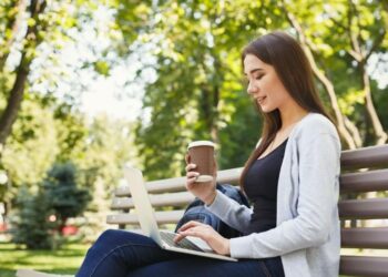 Mujer con portatil tomando un café en el parque
