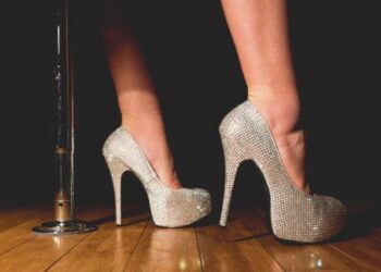 Tacones brillantes delante de barra de striptease