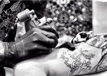 Profesional tatuando de forma realista en el brazo