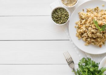 Mesa con plato de arroz, guisantes y cilantro